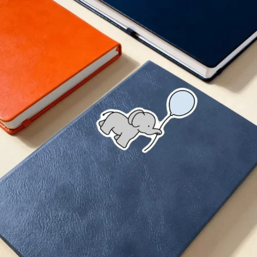 A cute elephant holding a balloon sticker ideal for laptops, diaries, bottles, and more, perfect as an adorable and whimsical gift.