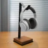 L Shaped Headphone Stand with a sleek black metal frame and premium wooden base holding white over-ear headphones on a wooden desk, showcasing a minimalist and modern workspace design.